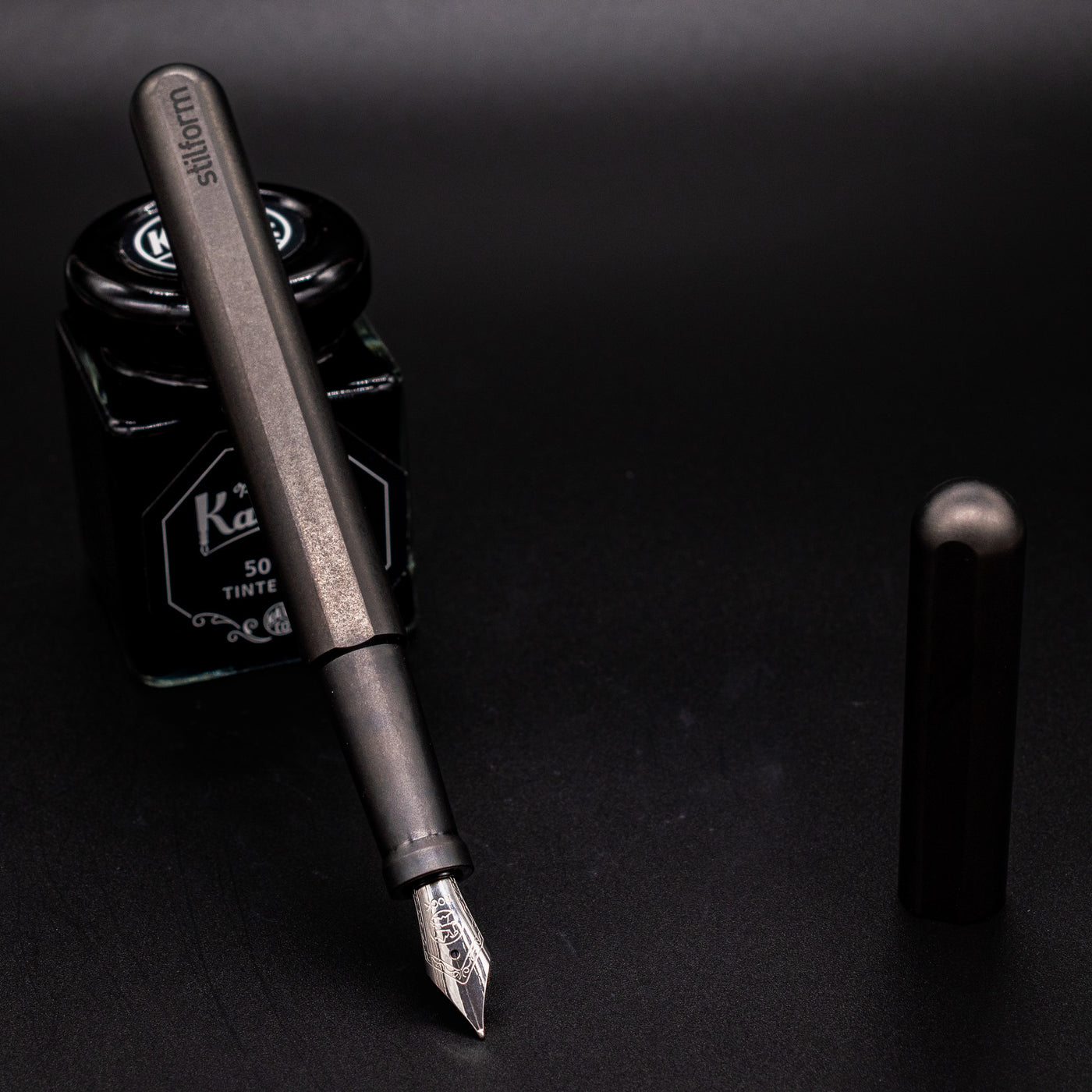 Stilform INK Fountain Pen Titanium Matte – uncapped and leaning on ink bottle
