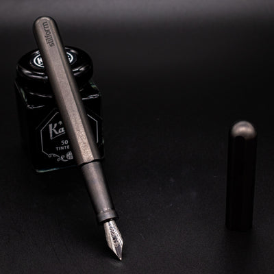 Stilform INK Fountain Pen Titanium Matte – uncapped and leaning on ink bottle