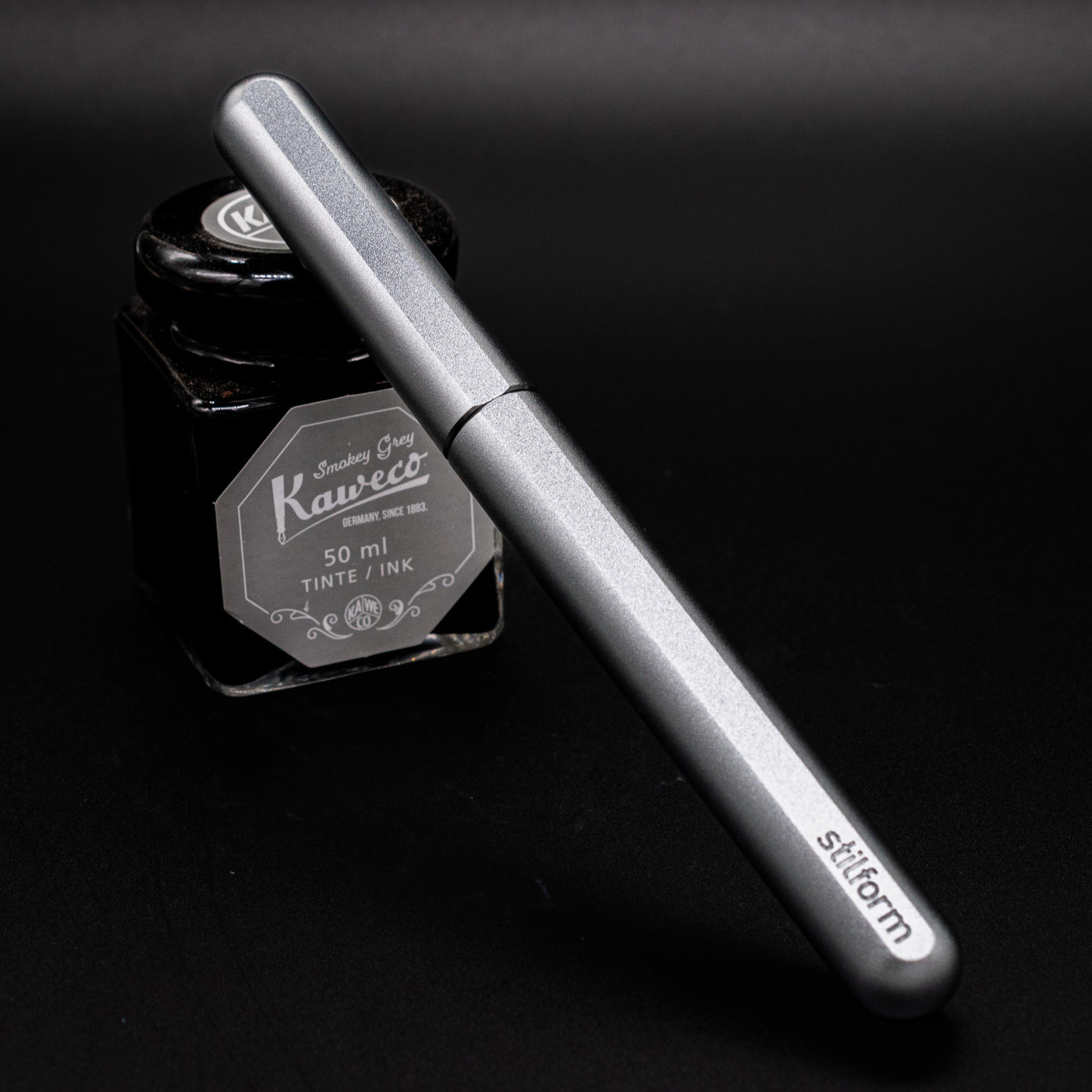 Stilform INK Fountain Pen Warp Black – capped and leaning on ink bottle