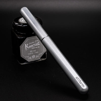Stilform INK Fountain Pen Warp Black – capped and leaning on ink bottle