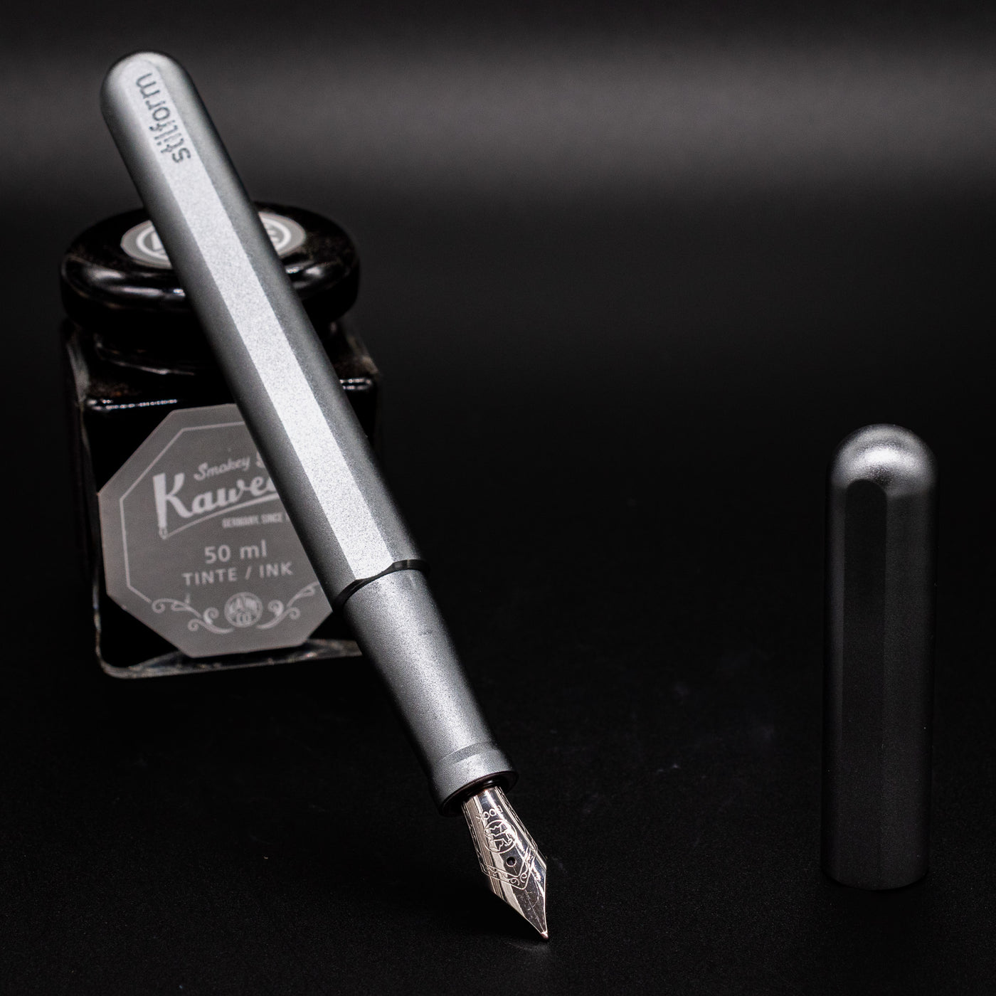 Stilform INK Fountain Pen Warp Black – uncapped and leaning on ink bottle