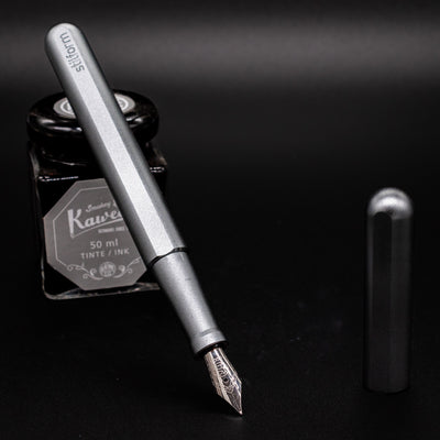 Stilform INK Fountain Pen Warp Black – uncapped and leaning on ink bottle
