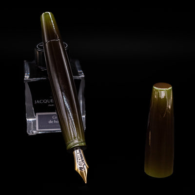 Taccia Olive Green Gradiation Urushi Fountain Pen with nib exposed, displayed on Jacques Herbin Gris de Houle ink bottle
