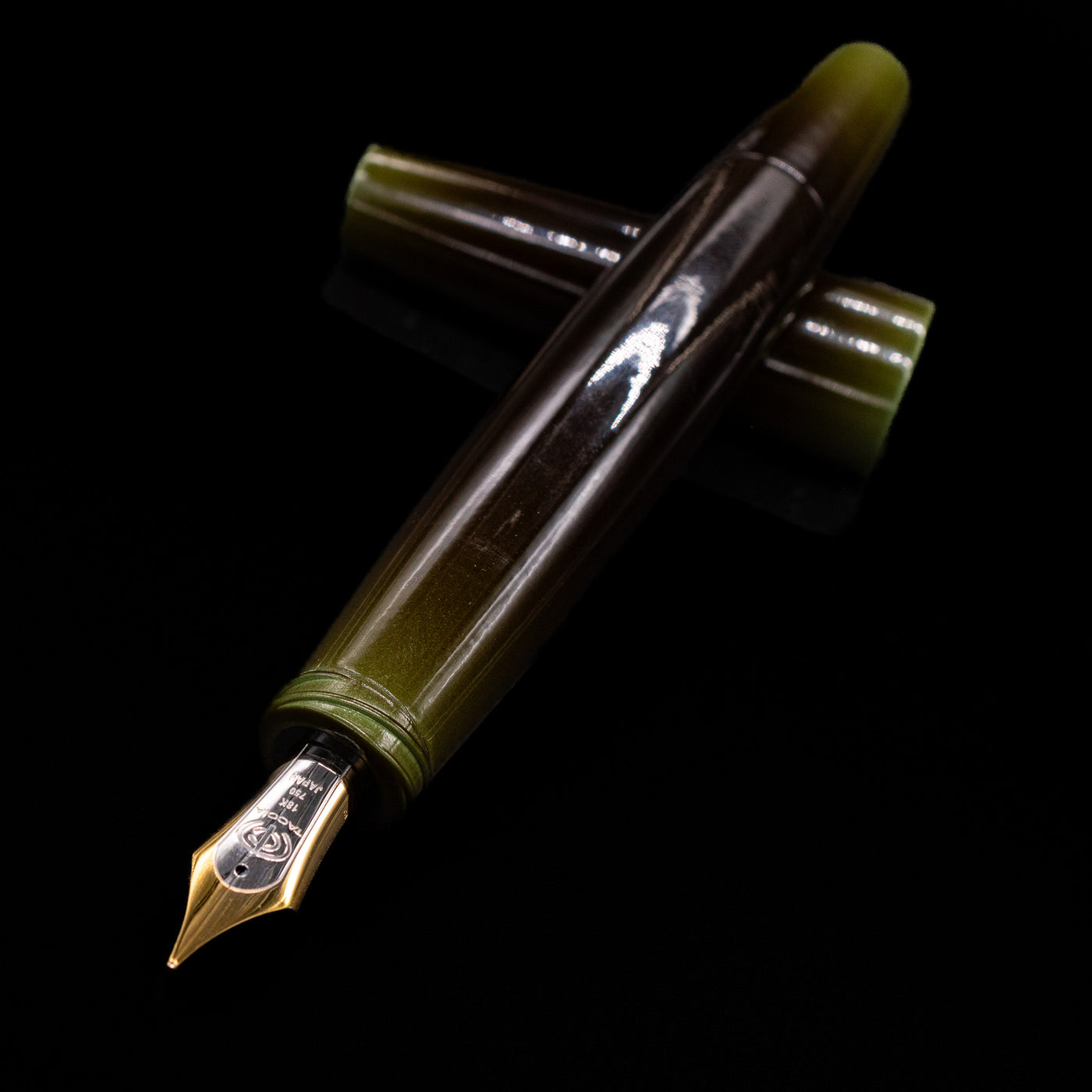Taccia Olive Green Urushi Fountain Pen shown uncapped with cap beside it on black background
