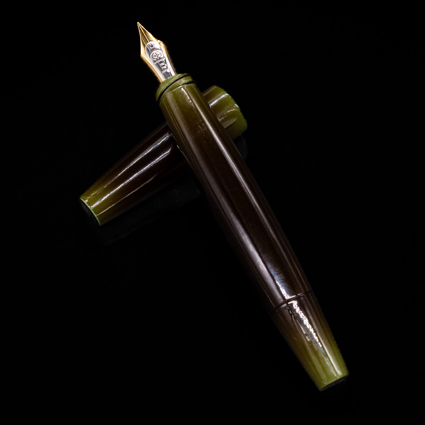 Top-down view of Taccia Olive Green Gradiation Urushi Fountain Pen with gold nib and cap placed horizontally