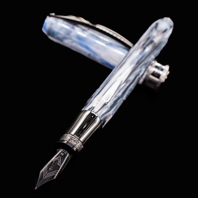 Close-up of Visconti Comedia Caronte Fountain Pen with nib and marbled resin cap on black background.