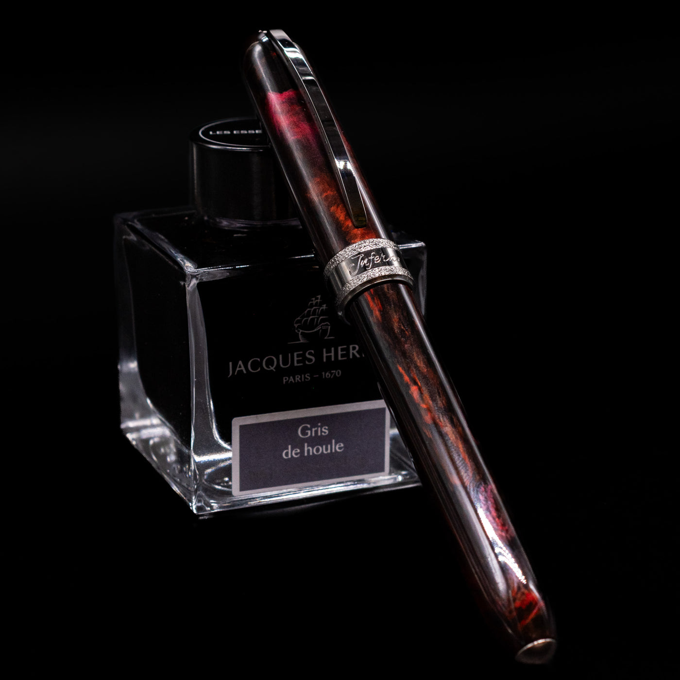 Full view of the Visconti Comedia Inferno Fountain Pen with cap on, displayed against Jacques Herbin ink