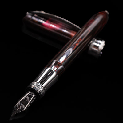 Close-up of the Visconti Comedia Inferno Fountain Pen nib and grip section with cap in background