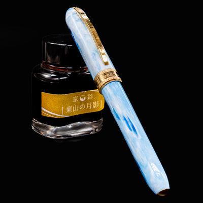 Visconti Comedia Paradiso fountain pen capped and resting on yellow-labeled ink bottle.