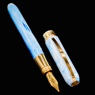 Disassembled Visconti Comedia Paradiso fountain pen with gold nib and cap beside barrel.