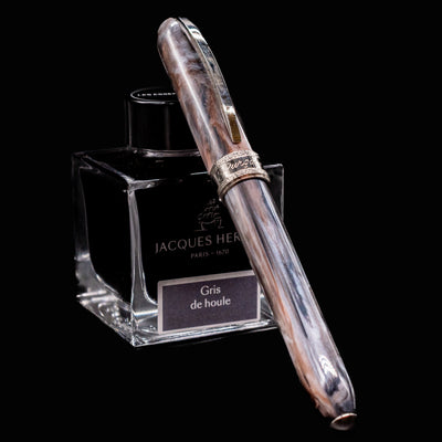 Visconti Comedia Purgatorio fountain pen closed with cap resting on Jacques Herbin ink bottle