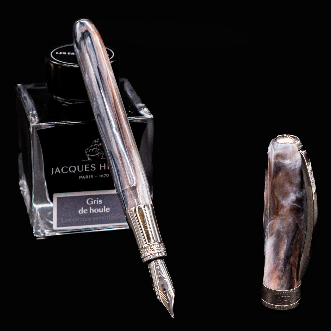 Visconti Comedia Purgatorio fountain pen uncapped with Jacques Herbin Gris de Houle ink bottle on black background