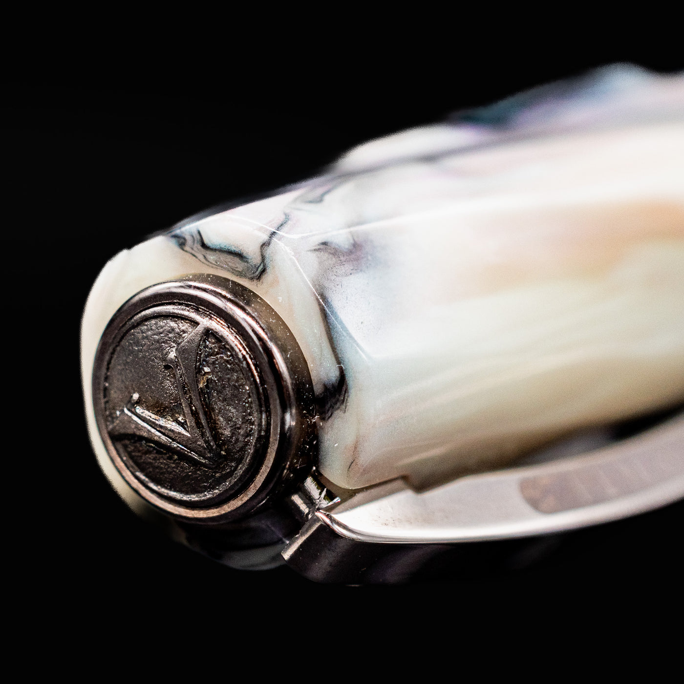 Close-up of the Visconti Divina Abalone Serial #1 cap finial with engraved V logo