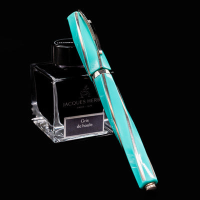Visconti Divina Elegance Wave Fountain Pen resting on Jacques Herbin Gris de Houle ink bottle