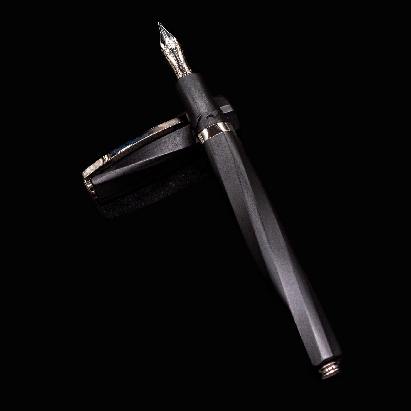 Full view of Visconti Divina Matte Black Fountain Pen with cap placed beside the faceted barrel