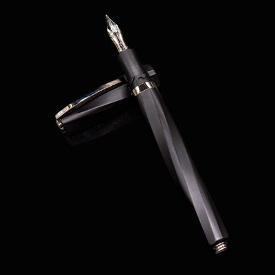 Full view of Visconti Divina Matte Black Fountain Pen with cap placed beside the faceted barrel
