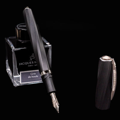 Uncapped Visconti Divina Matte Black Fountain Pen next to Jacques Herbin ink bottle with silver nib exposed