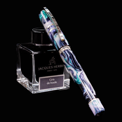 Visconti Homo Sapiens Earth Origins Air fountain pen capped and resting on Jacques Herbin ink bottle