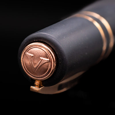 Close-up of a Visconti pen with a bronze cap top and logo on a black background