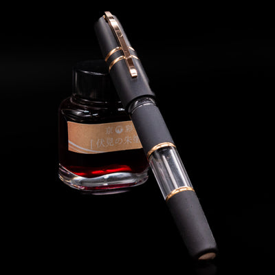 Visconti fountain pen, capped, with ink bottle on a black background