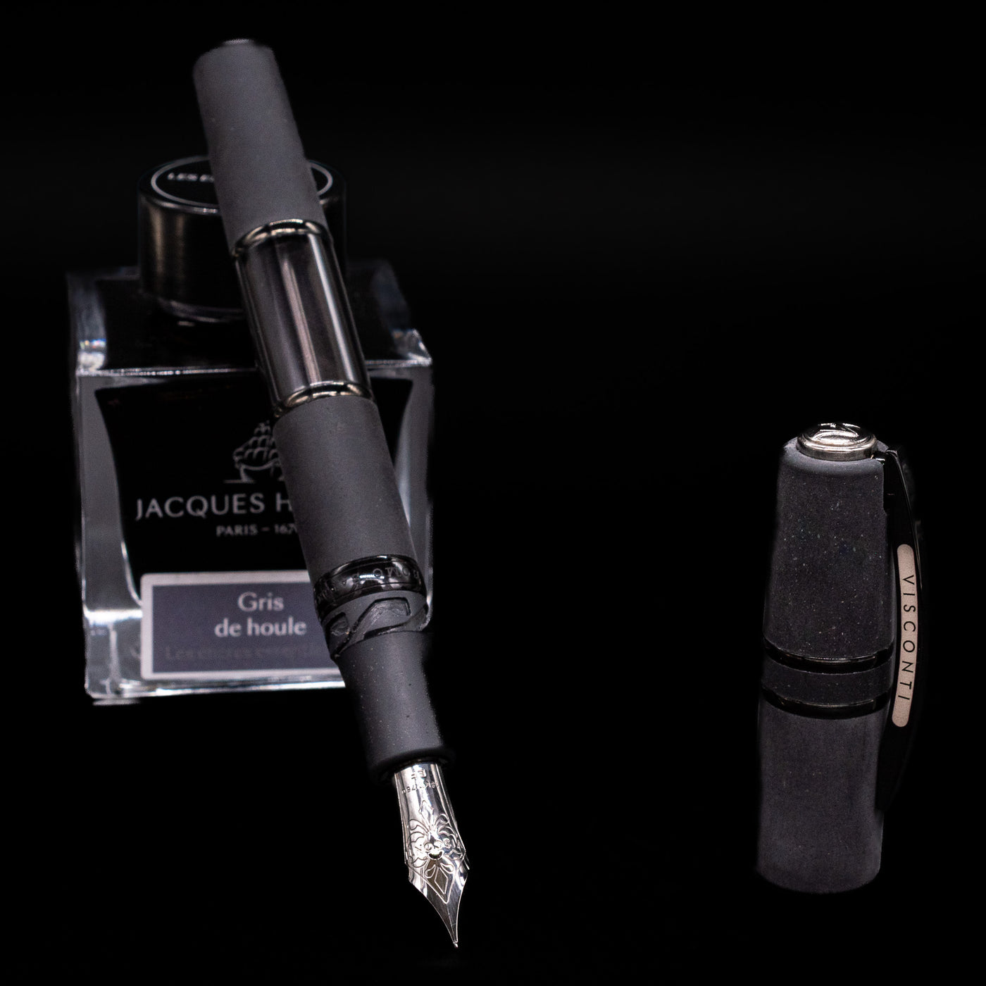 Black Visconti Homo Sapiens Dark Crystal fountain pen leaning on a Jacques Herbin ink bottle, based on a black background