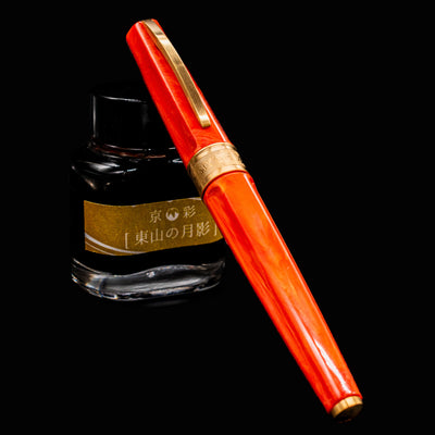 Visconti Mirage Mythos Fountain Pen Demeter fully capped and resting on ink bottle with orange marbled resin and bronze trim