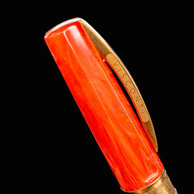 Close-up of Visconti Mirage Mythos Demeter cap and clip engraved with VISCONTI branding against marbled orange resin