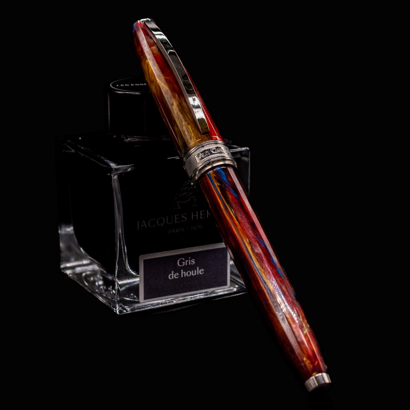 Visconti Van Gogh Red Vineyard Fountain Pen resting on Jacques Herbin ink bottle with a striking marbled red, orange, and blue resin body