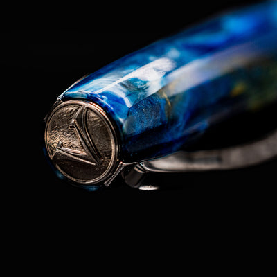 Macro of the Visconti Van Gogh Starry Night pen cap finial with raised Visconti logo and deep blue marbled finish.
