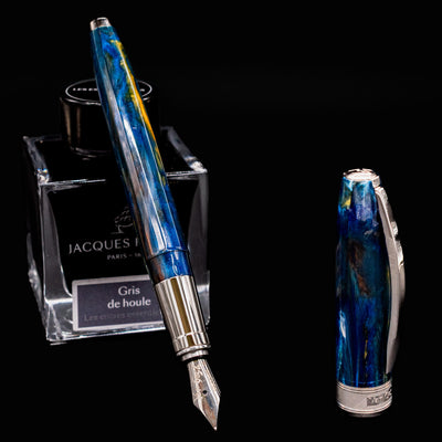 Visconti Van Gogh Starry Night Fountain Pen uncapped with nib exposed and cap standing beside Jacques Herbin ink bottle.