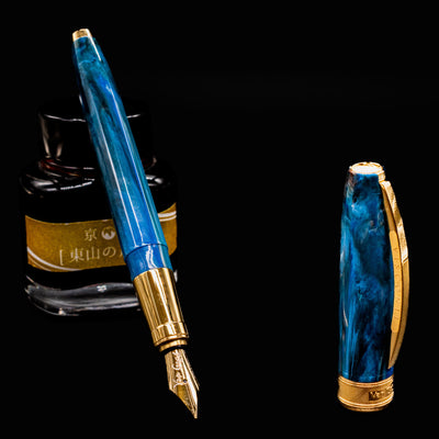 Uncapped Visconti Van Gogh Wheatfield with Crows fountain pen beside ink bottle, revealing the gold nib and textured resin barrel.