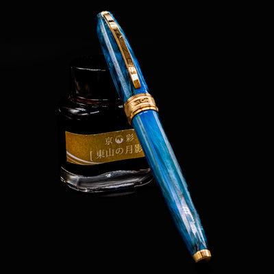 Visconti Van Gogh Wheatfield with Crows fountain pen resting on Japanese ink bottle, showcasing swirling blue acrylic and gold trim.