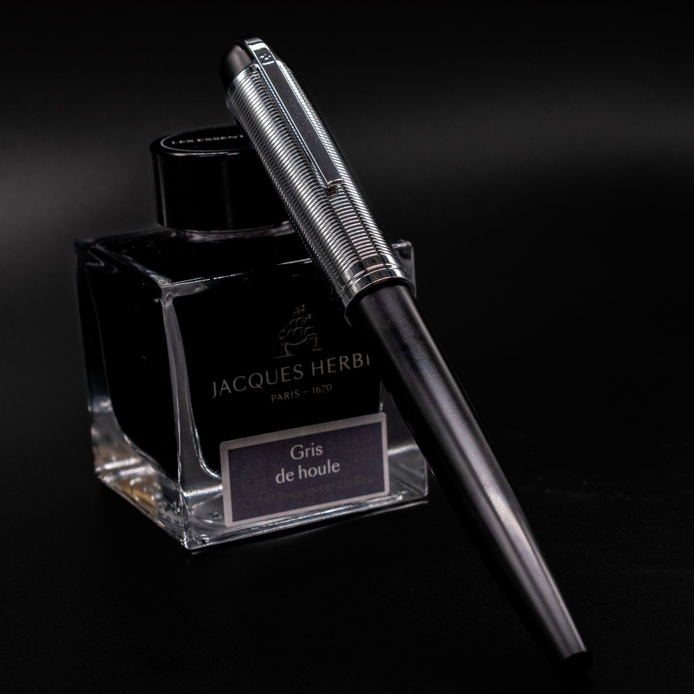 Wahl Eversharp Skyline Fountain Pen - Black & Chrome shown capped and resting against a Jacques Herbin ink bottle.