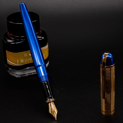 Wahl Eversharp Skyline Fountain Pen - Blue & Gold next to a bottle of ink, cap placed upright beside.