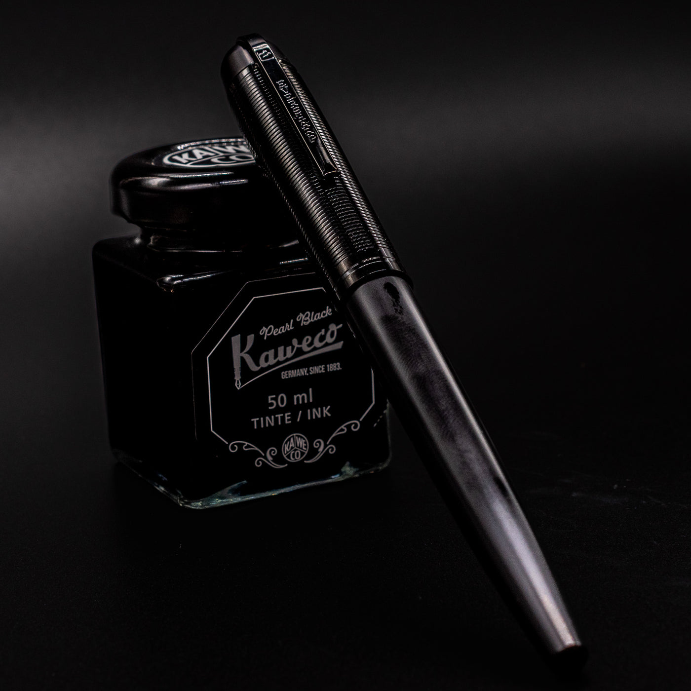 Capped Wahl Eversharp Skyline Fountain Pen - Aviator Black resting on Kaweco ink bottle for an elegant display shot.