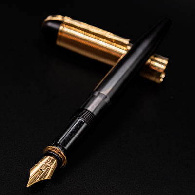 Angled view of the Wahl Eversharp Skyline Fountain Pen - Black & Gold with cap resting behind barrel
