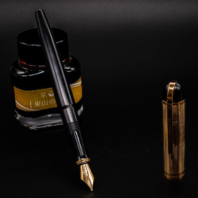 Wahl Eversharp Skyline Fountain Pen - Black & Gold uncapped and standing in front of a bottle of ink