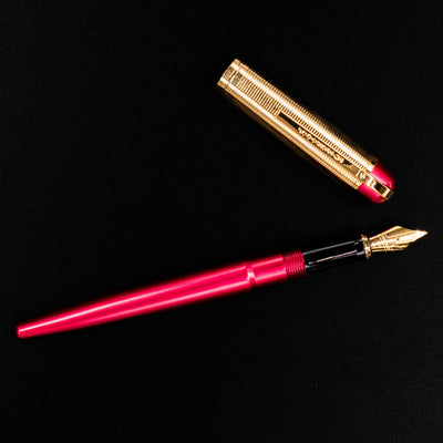 Flat lay of the open Wahl Eversharp Skyline Fountain Pen in Red & Gold next to its cap.